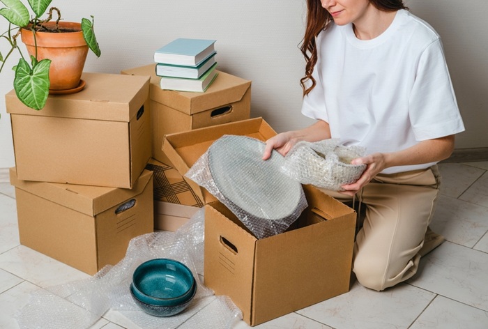femme qui emballe ses objets fragiles soigneusement pour son déménagement