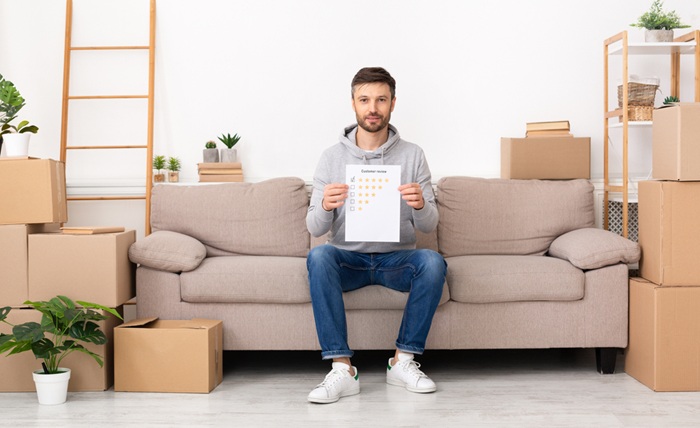 homme sur canapé au milieu de cartons de déménagement montrant les certifications déménagement de son devis